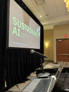 speaker podium with microphone in the foreground and large screen in the background reading "Sustainable AI"