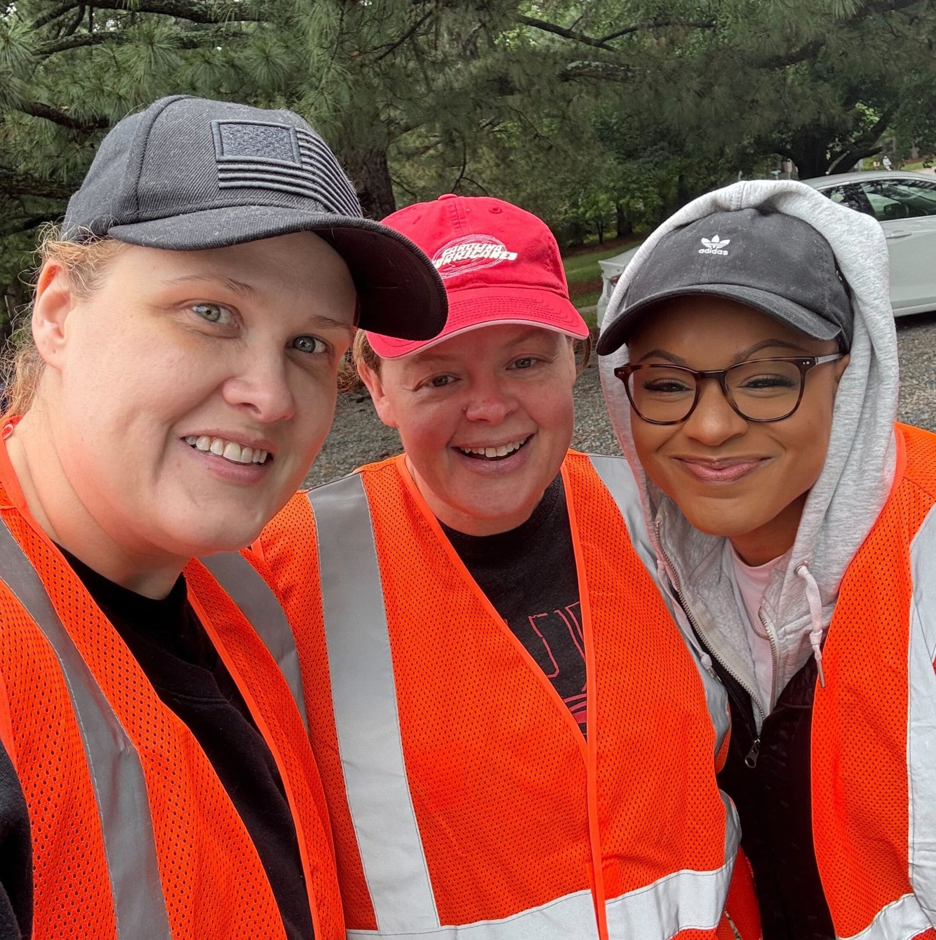 Three members of the Marit Digital team pose together for a selfie wearing baseball hats and orange safety vests.